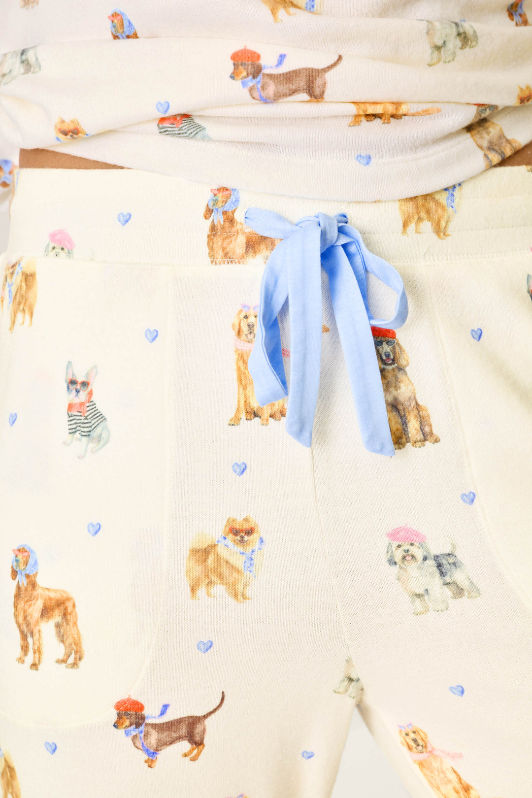 Close-up of the P.J. Salvage Meet Me in Pawris Dog Print Jogger Pajama Pants featuring colorful dog illustrations, tiny blue hearts, and a light blue drawstring at the waist.