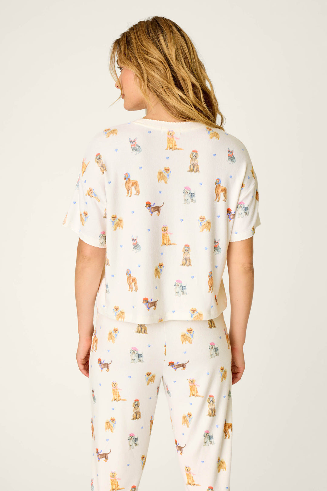 A woman with wavy blonde hair is shown from the back against a plain, light background, wearing the P.J. Salvage "Meet Me in Pawris Dog Print" Short Sleeve Top.