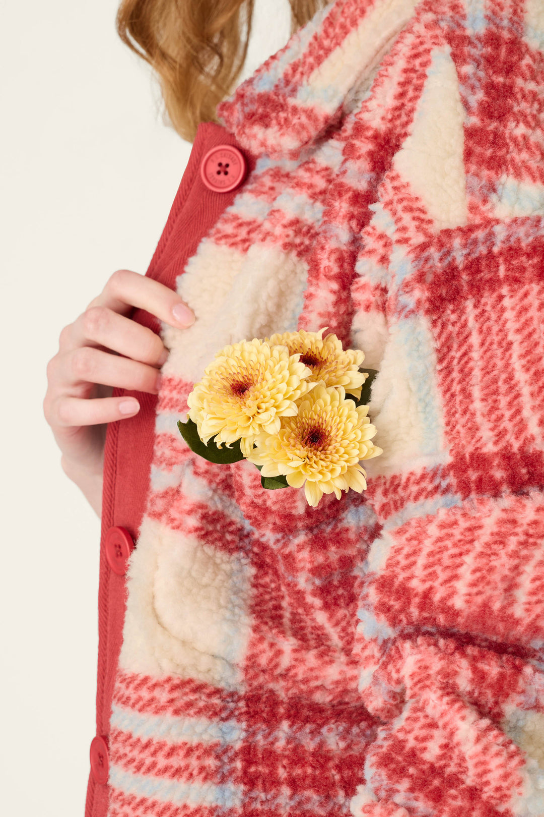 Wearing the P.J. Salvage Nature Is My Therapy Big Teddy Red Plaid Sherpa Jacket, a person holds yellow chrysanthemums tucked into the chest pocket.