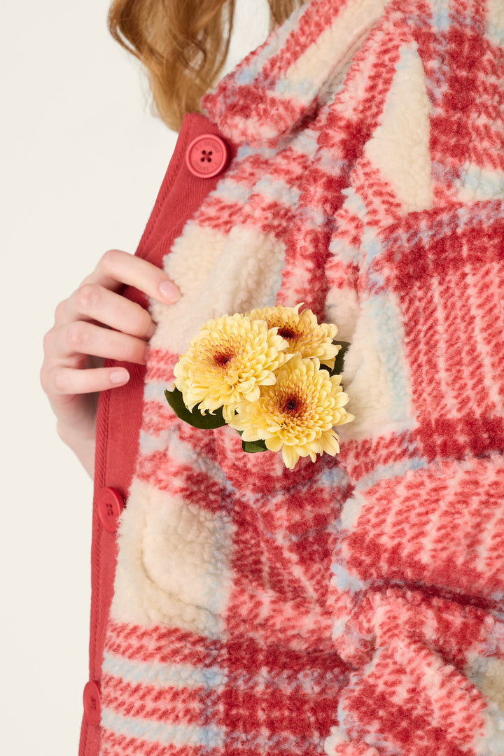 Wearing the P.J. Salvage Nature Is My Therapy Big Teddy Red Plaid Sherpa Jacket, a person holds yellow chrysanthemums tucked into the chest pocket.