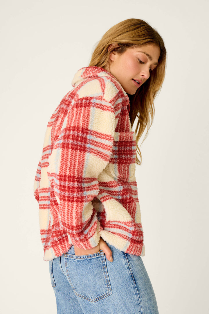 A woman stands sideways against a plain background, looking down with her hands in the pockets of her light blue jeans, wearing the P.J. Salvage Nature Is My Therapy Big Teddy Red Plaid Sherpa Jacket.