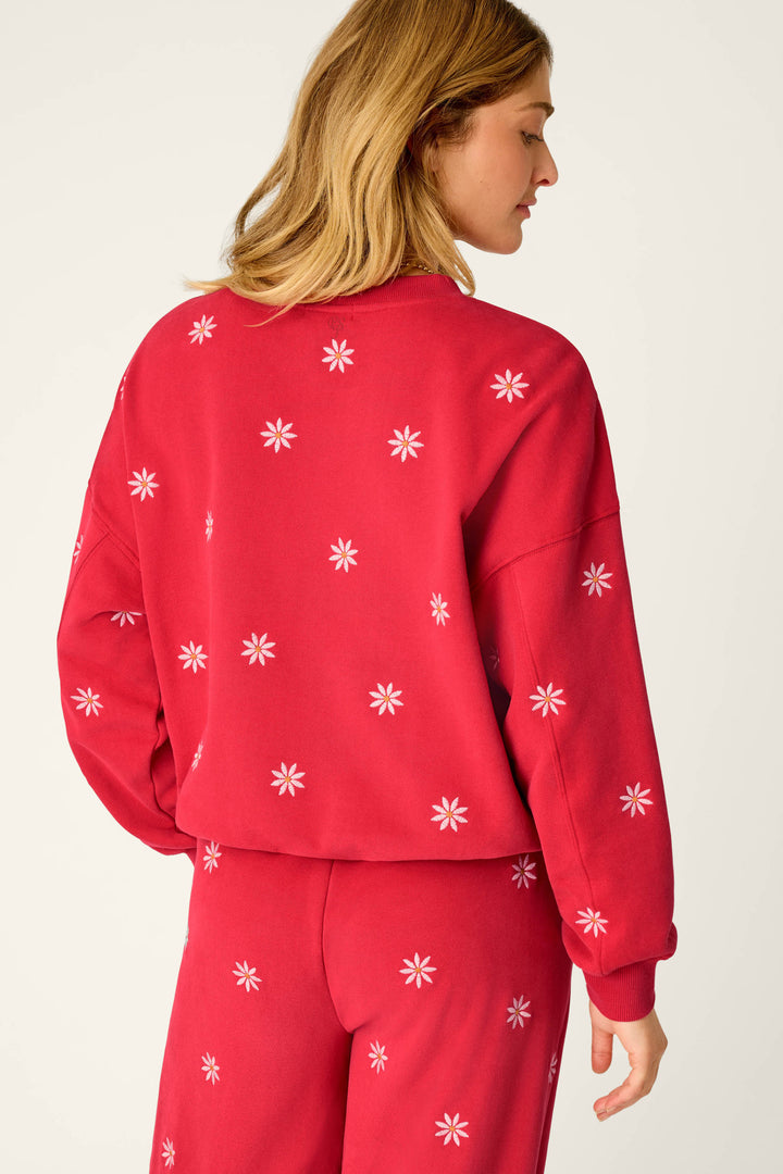 A woman with light brown hair is seen from the back, wearing a matching red set featuring the P.J. Salvage “Nature Is My Therapy Embroidered Flowers Frankie Sweatshirt,” adorned with small white flower patterns.