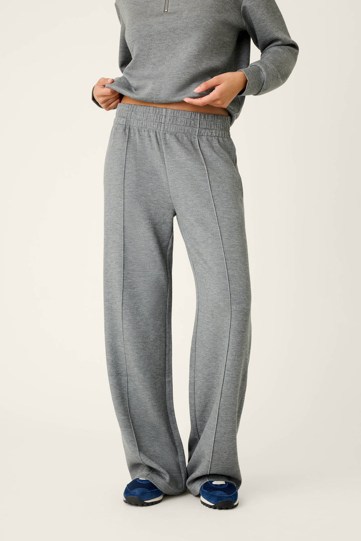 A person is shown from the neck down wearing P.J. Salvage Nature Is My Therapy Runway Lounge Pants in gray with a matching sweatshirt, standing against a light background and paired with dark blue sneakers.
