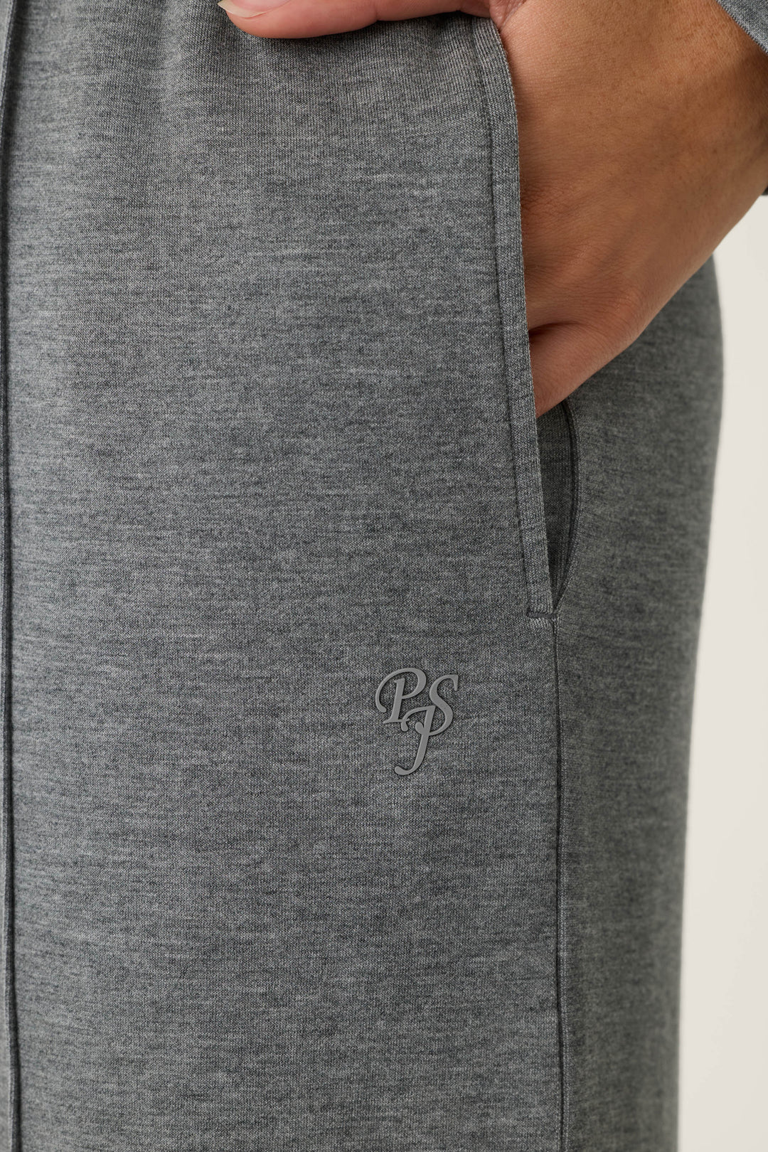 A close-up of a person’s hand in the pocket of gray Nature Is My Therapy Runway Lounge Pants by P.J. Salvage, with the initials “PS” embroidered near the pocket.