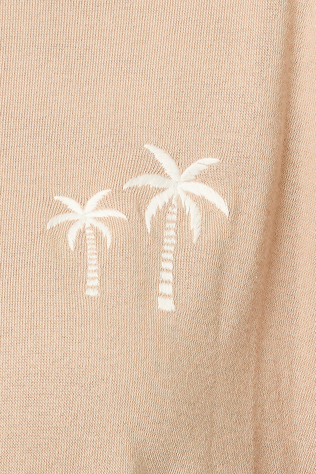 Close-up of the P.J. Salvage Palms Away Warm Taupe Sweatshirt shows two small white embroidered palm trees, one slightly taller than the other, stitched side by side on beige fabric.