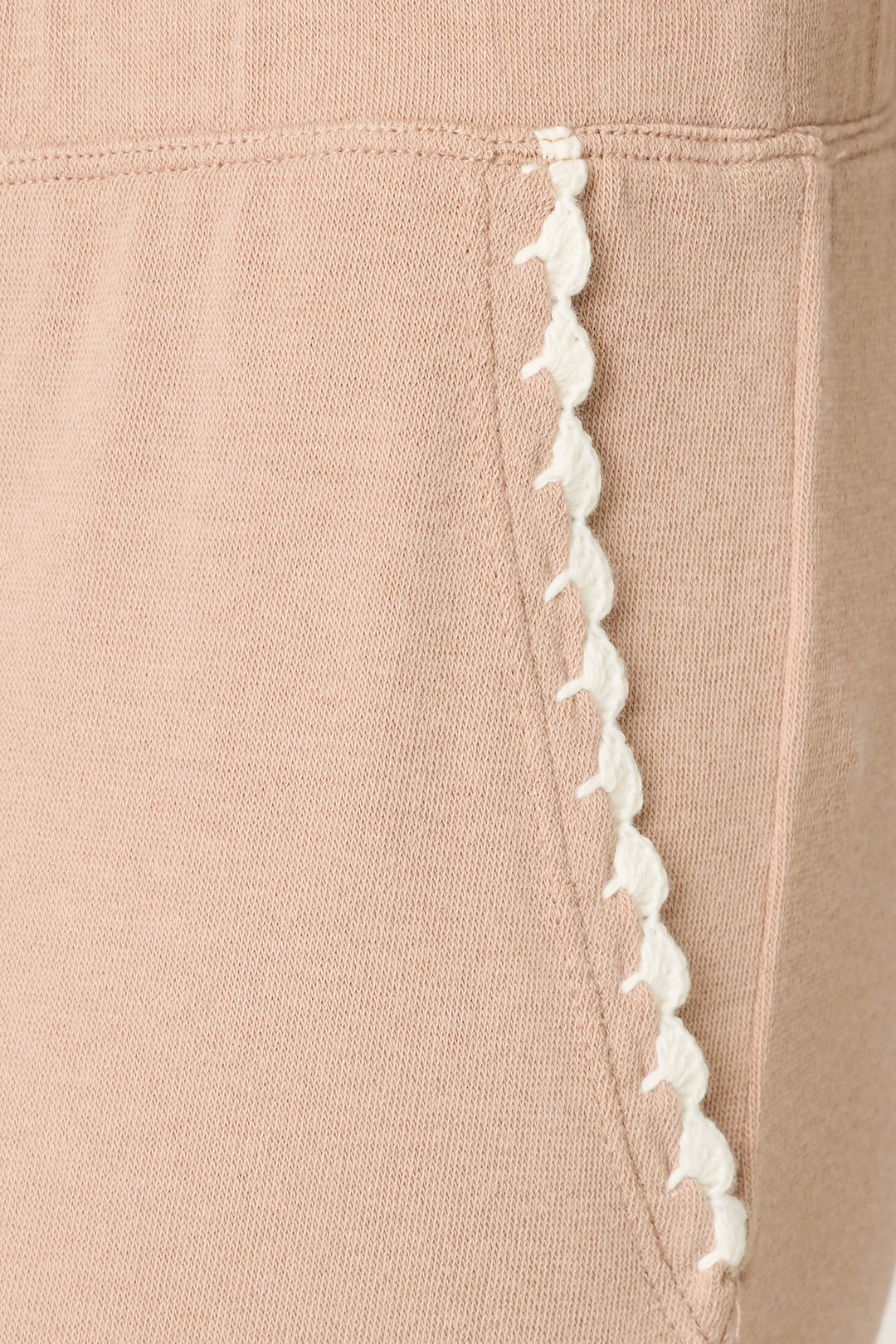 Close-up of the Palms Away Warm Taupe Open Leg Pants by P.J. Salvage, featuring a beige fabric pocket with white scalloped trim along the edge, detailed stitching, and soft knit material.