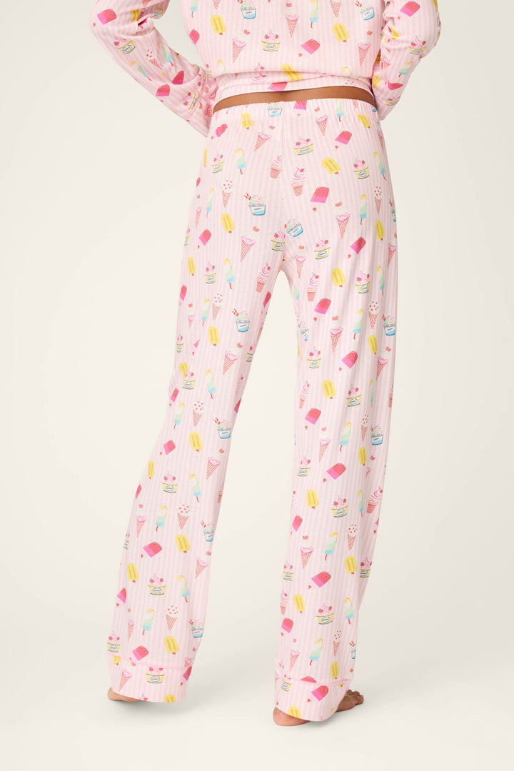 Wearing P.J. Salvage’s Playful Prints Sugar Rush Pajama Pants—pink with vibrant dessert prints—in soft cotton-modal jersey, shown waist down and barefoot against a plain background.