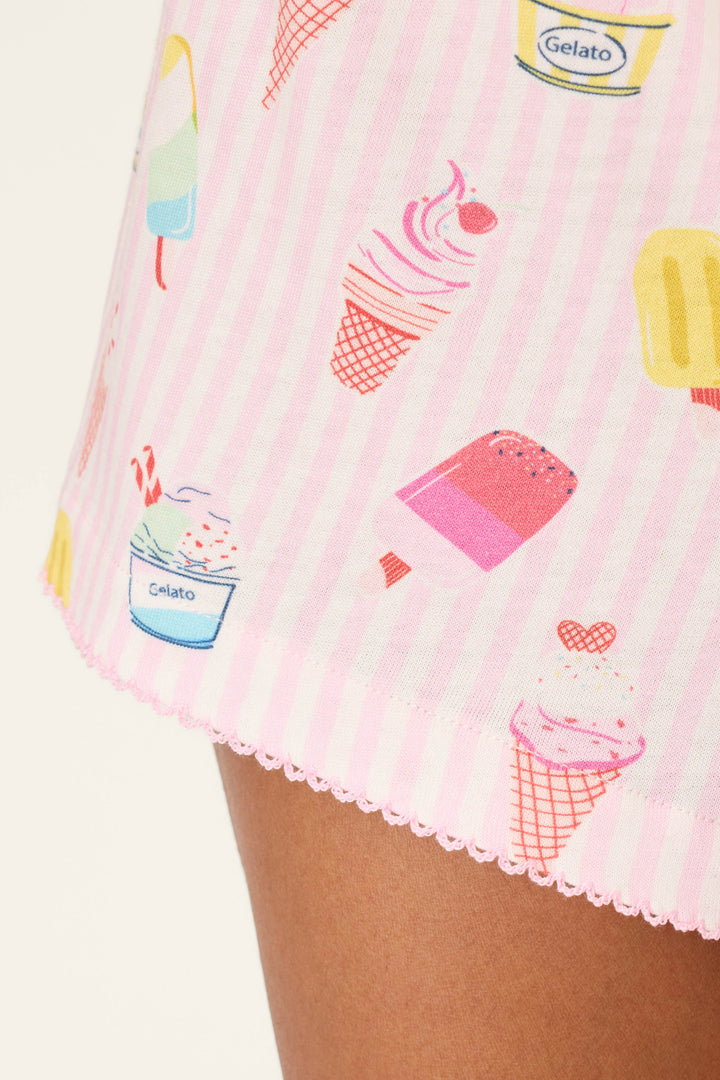 Close-up of P.J. Salvage Playful Prints Sugar Rush Sleep Shorts—pink and white stripes with a vibrant gelato print—worn on a person’s leg, capturing the fun, summery charm of the collection.