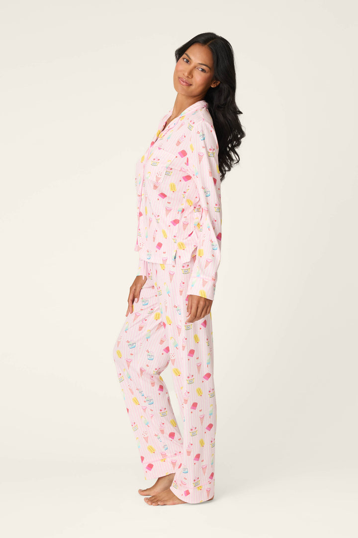 A woman stands barefoot, smiling gently in the P.J. Salvage Playful Prints Sugar Rush Long PJ Set, crafted from soft cotton-modal jersey, against a plain light background.