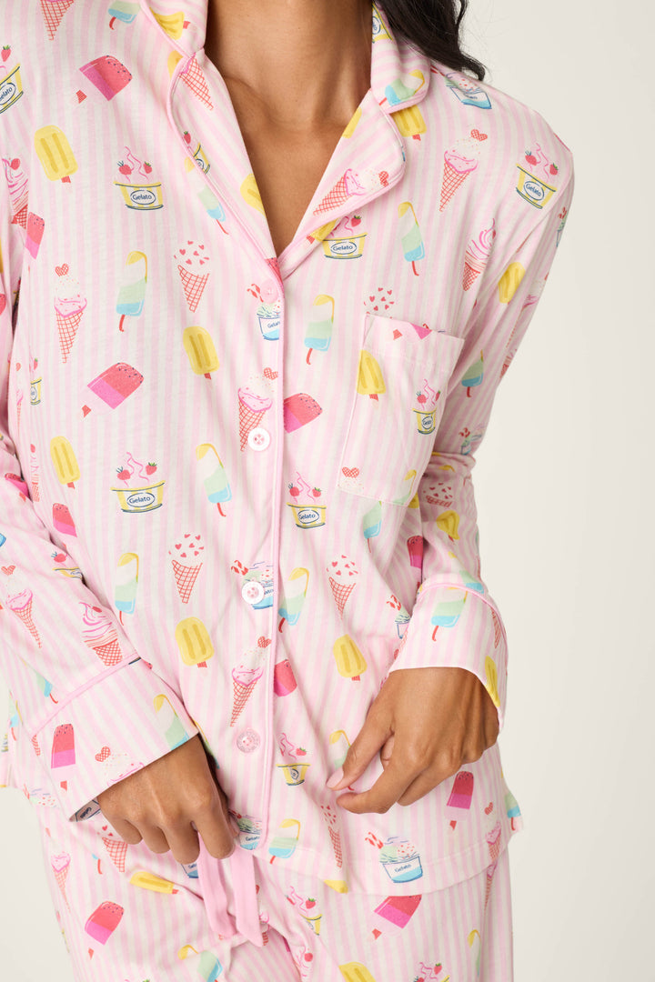 A woman models the P.J. Salvage Playful Prints Sugar Rush Long PJ Set, featuring a pastel cotton-modal jersey with colorful ice cream and popsicle designs. She holds her pajama top, her face partially out of frame.