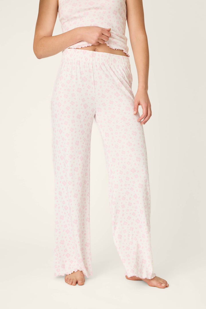 A person stands barefoot against a neutral background wearing P.J. Salvage's Pretty Petals Sweet Pink Floral Print Open Leg Pants; their face is not visible.