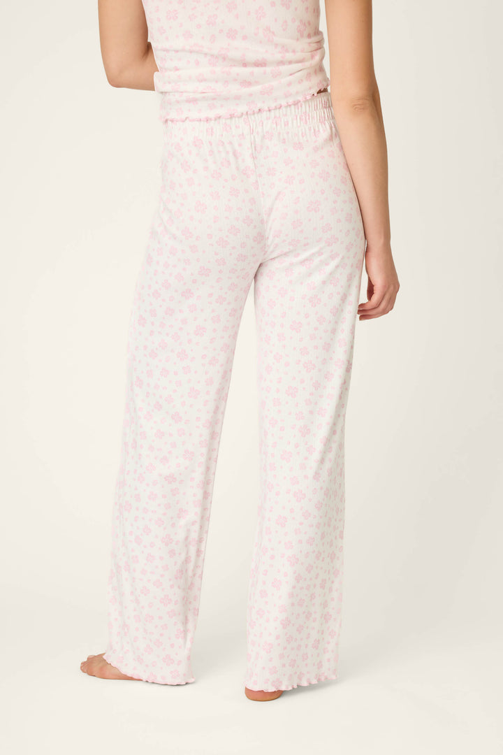 A person is barefoot, seen from the back, wearing P.J. Salvage Pretty Petals Sweet Pink Floral Print Open Leg Pants and a matching sleeveless floral top. The background is plain and light-colored.