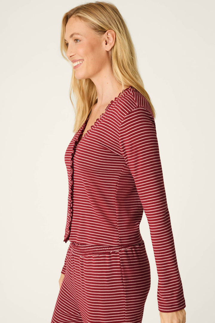 A woman with long blonde hair, smiling and standing sideways against a plain light background, is wearing the P.J. Salvage Pretty Stripes Dark Wine Pointelle Cardigan.