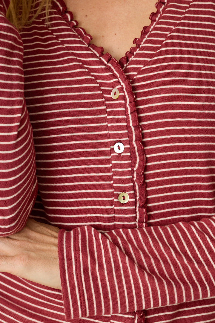 A person wearing the P.J. Salvage Pretty Stripes Dark Wine Pointelle Cardigan, which features red and white stripes with scalloped trim and buttons, is crossing one arm over their body.