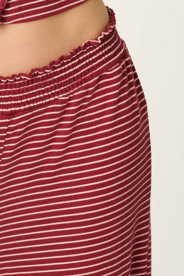 A close-up of a person wearing the P.J. Salvage Pretty Stripes Dark Wine Pointelle Pajama Pants, showcasing the waistband and hem with a small gap of skin visible between the matching striped set.