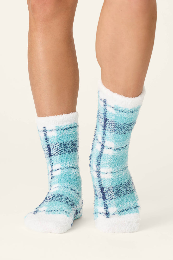 A person wearing the P.J. Salvage Plaid About You Blue & Green Plaid Socks stands on a light background, with only their lower legs and feet visible.