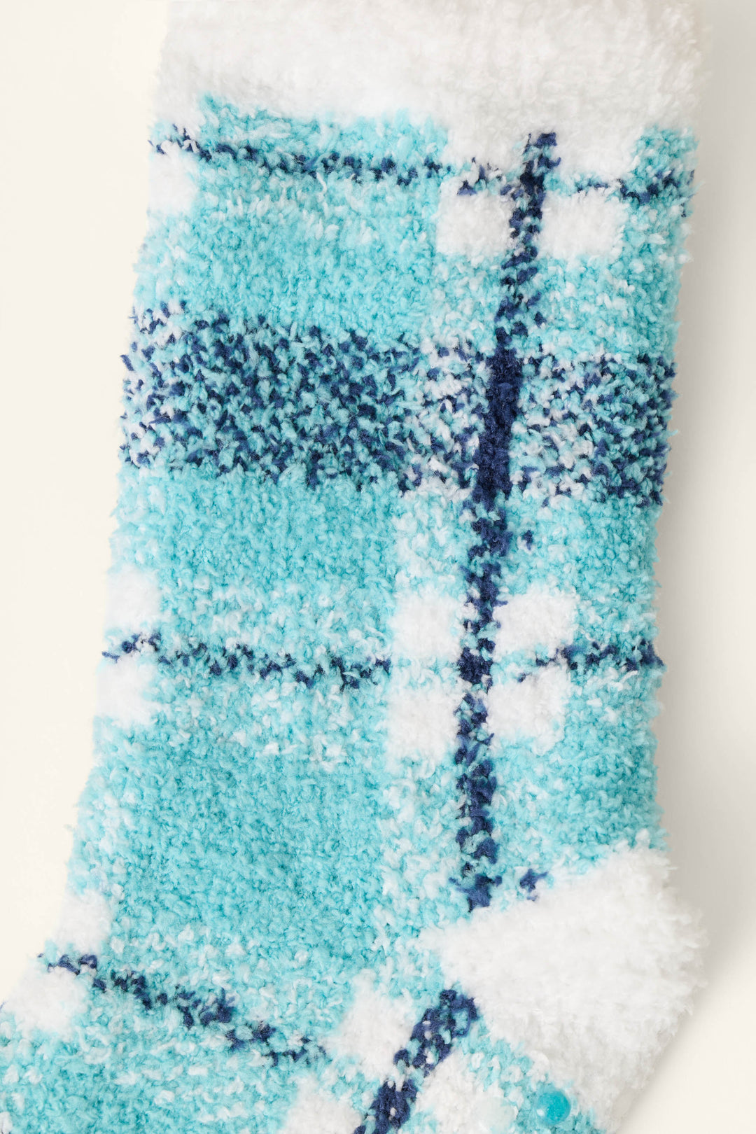 A close-up of the P.J. Salvage Plaid About You Blue & Green Plaid Socks displayed on a soft, textured fabric.
