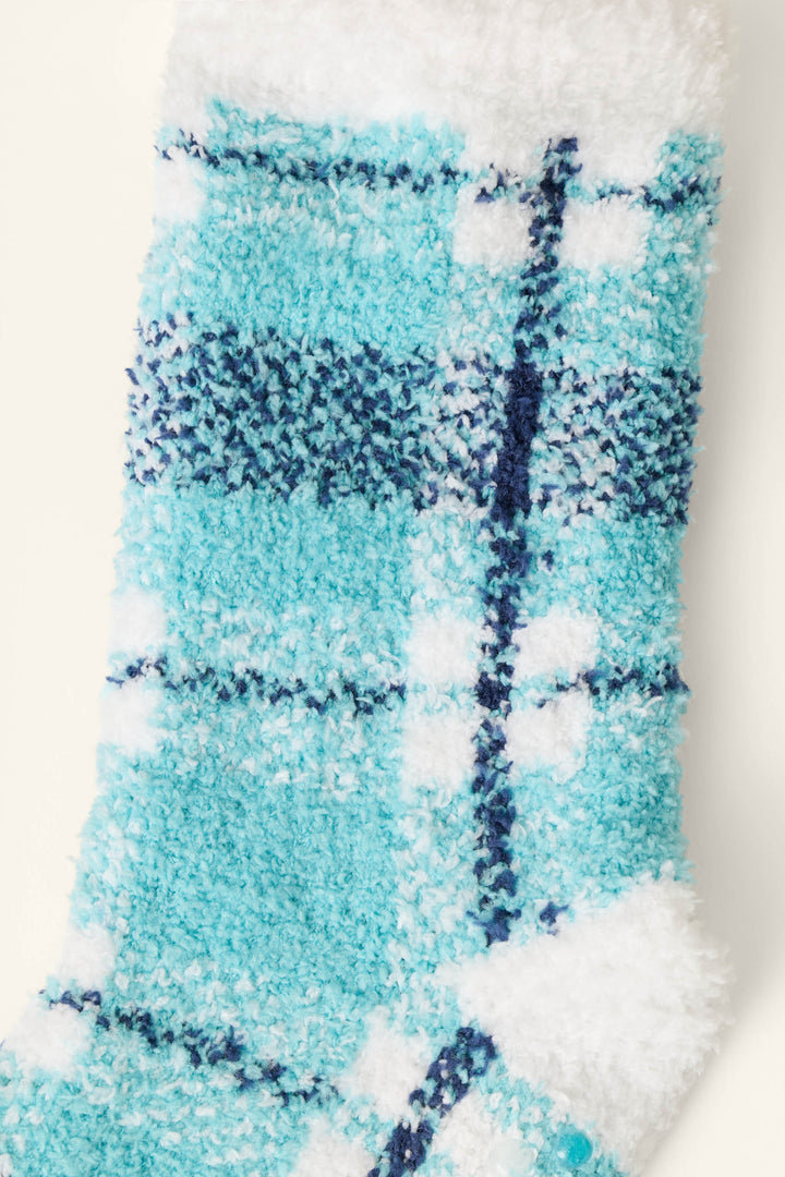 A close-up of the P.J. Salvage Plaid About You Blue & Green Plaid Socks displayed on a soft, textured fabric.