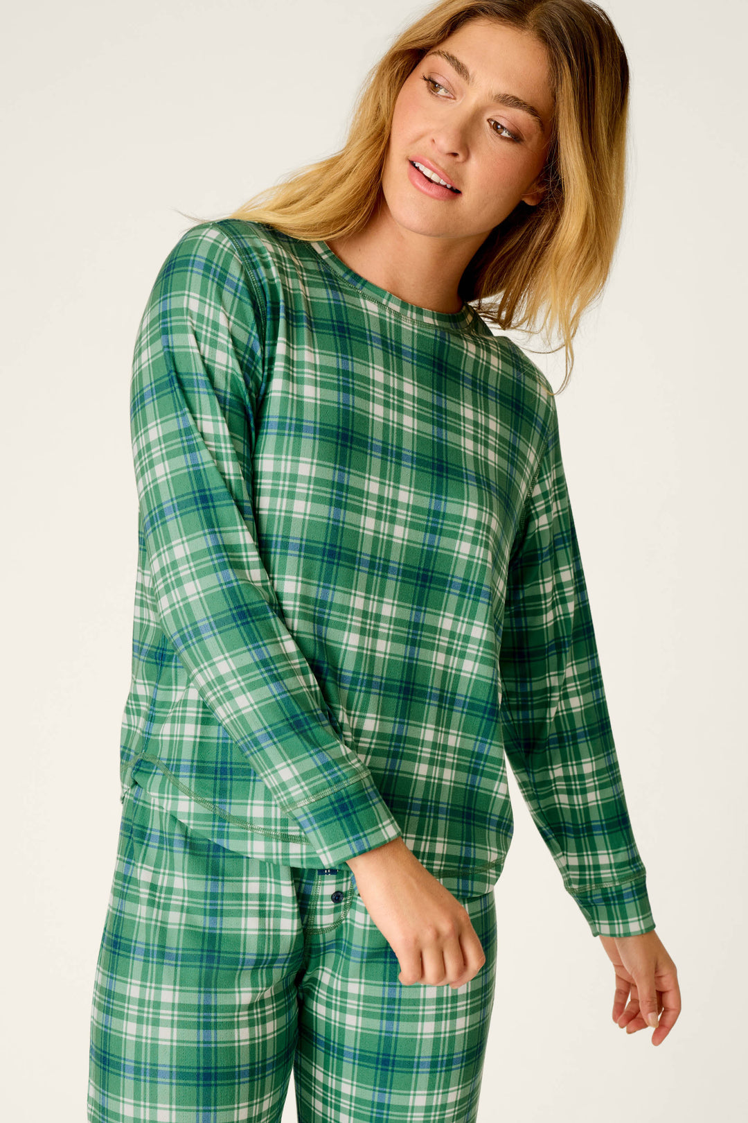 A woman with long blonde hair stands against a plain background, looking slightly to the side with a relaxed and gentle expression while wearing the P.J. Salvage Plaid About You Blue & Green Plaid Print Long Sleeve Top.