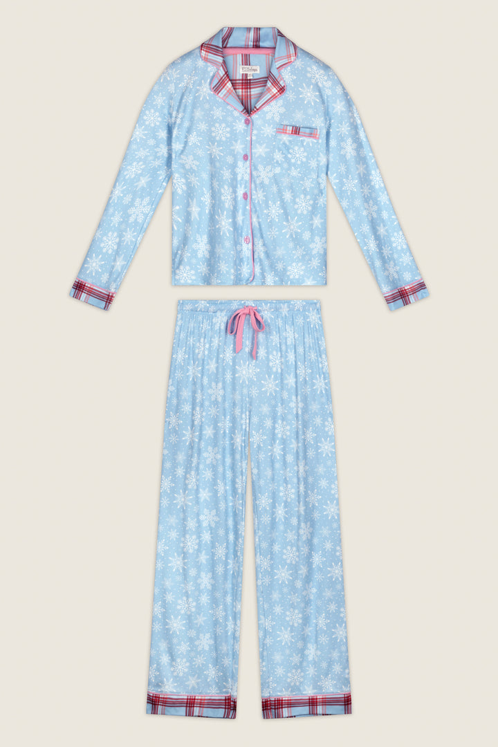 The Plaid About You Snowflakes & Plaid PJ Set by P.J. Salvage features a two-piece design with a blue snowflake pattern and red plaid trim on the collar, cuffs, and hem. The button-up top includes a chest pocket, while the pants offer a drawstring waist and plaid accents at the ankles.