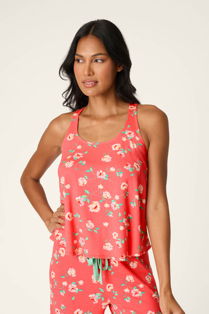 A woman wears the P.J. Salvage Siesta Dreams Dark Coral Floral Print Tank Top, part of a matching set, standing with one hand on her hip against a plain background.