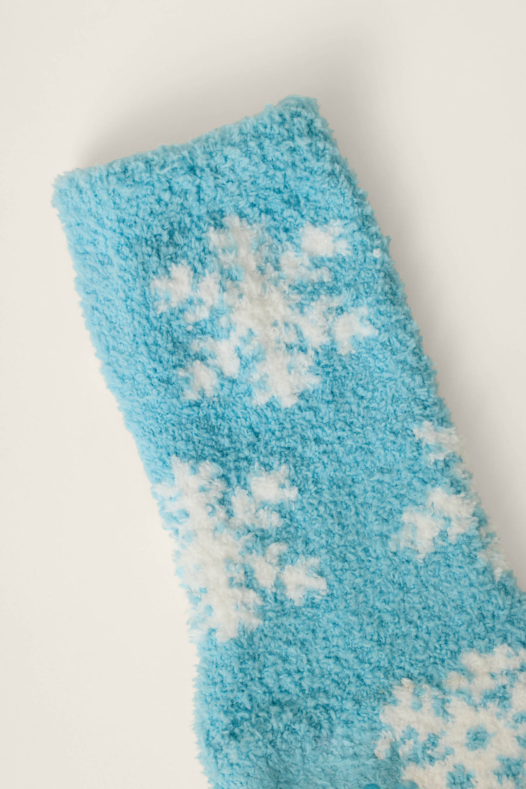The Ski Jammie Classics Snowflake Print Socks by P.J. Salvage are displayed on a white background, featuring a fuzzy blue fabric with white snowflake patterns.