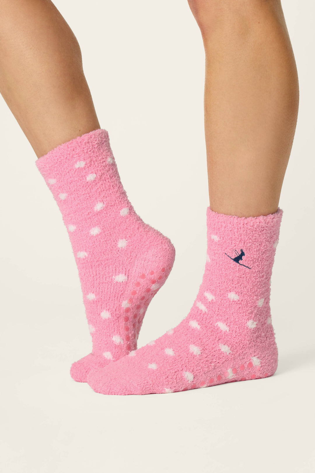 A person stands on a light background with one foot slightly in front of the other, wearing P.J. Salvage Ski Jammie Classics Ski Bunny & Snowflakes Socks.