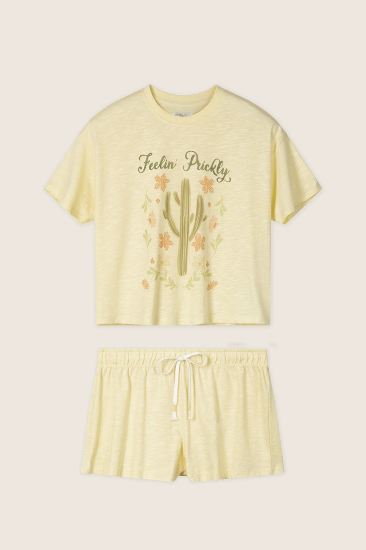 The P.J. Salvage Softee "Feelin' Prickly" Graphic Print Short PJ Set features a light yellow relaxed fit with a cactus design crop top reading "Feelin' Prickly" and comfy shorts with an elastic waistband and drawstring.