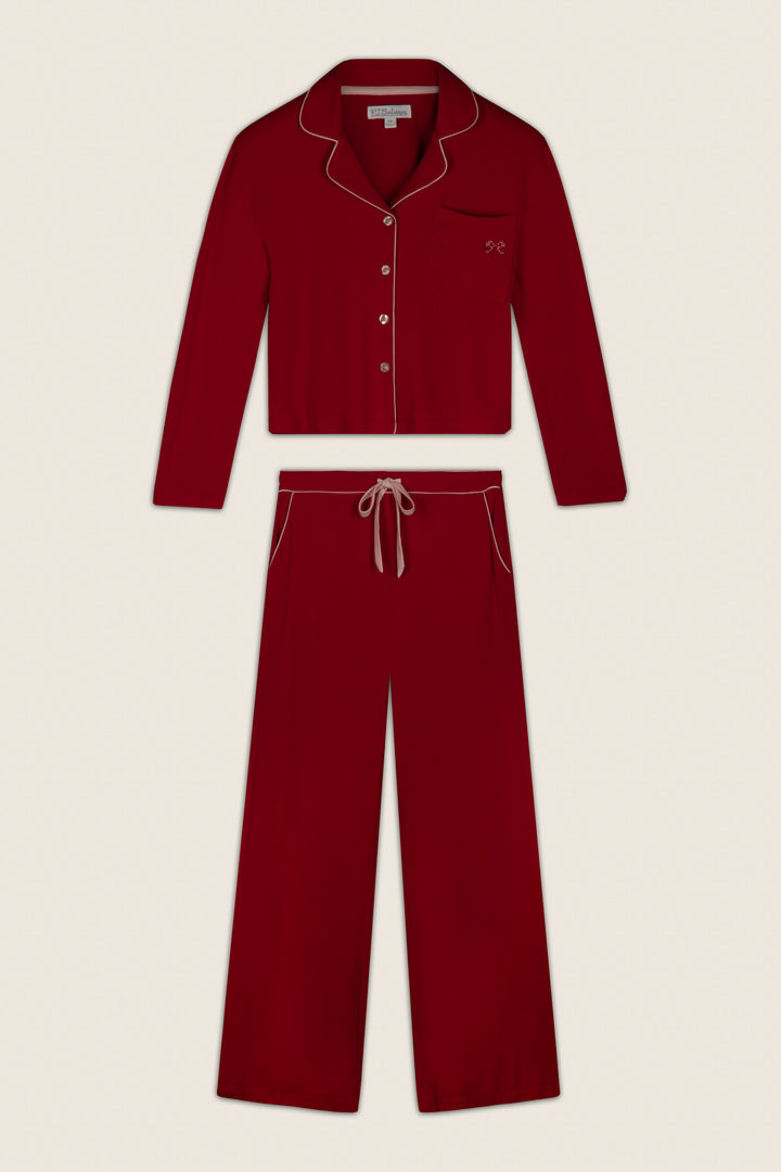 The Sweetheart Dreams Red Long Sleeve PJ Set by P.J. Salvage, featuring white piping, a collared button-up top with a front chest pocket, and matching drawstring pants, is laid flat on a plain background.