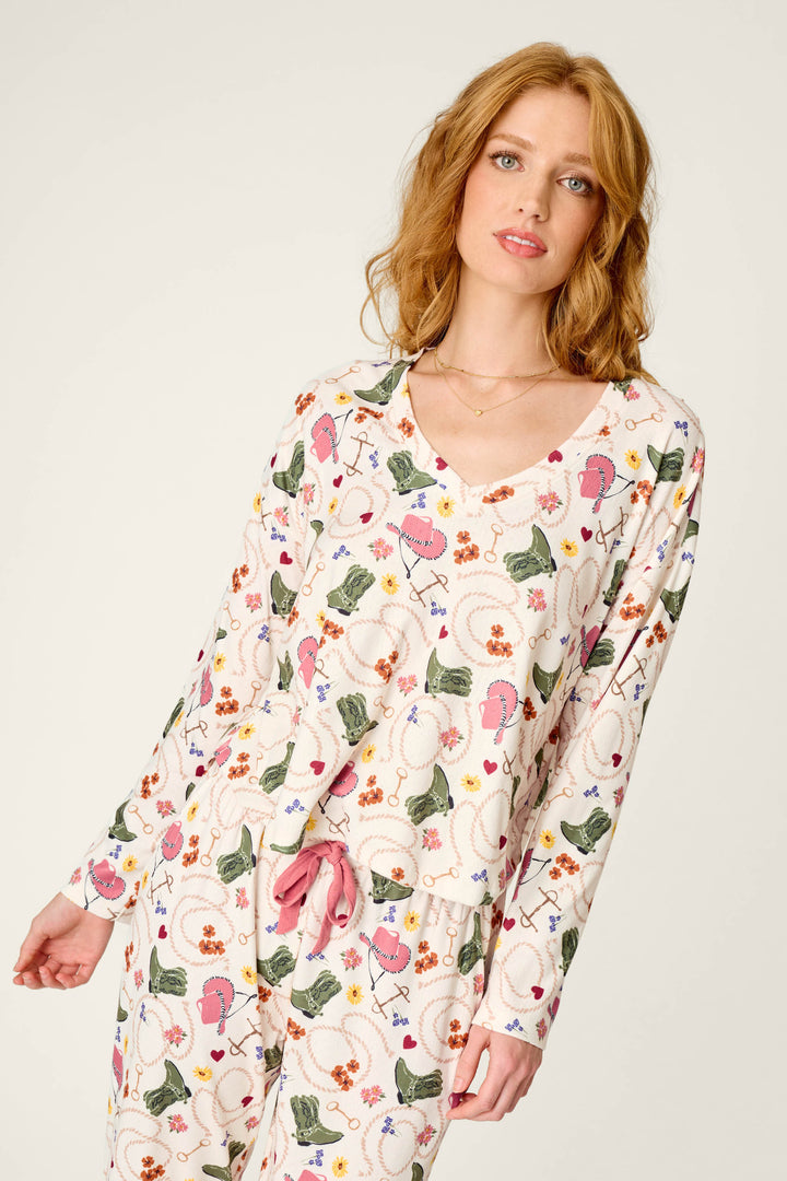 A woman wearing the P.J. Salvage Saddle Up Western Print Long Sleeve V-Neck Top poses against a light background.