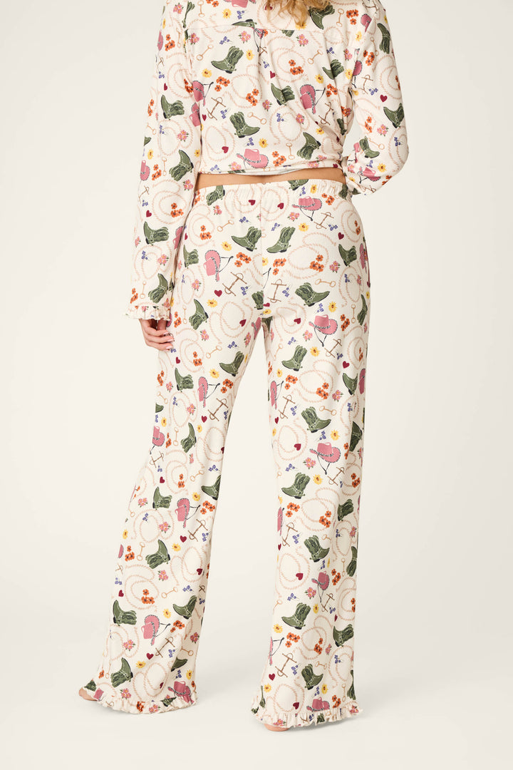A person wearing the P.J. Salvage Saddle Up Western Print Pajama Pants, photographed from the back, showcasing the long-sleeve top and wide-leg pants with ruffled hems featuring a vibrant western-inspired print.
