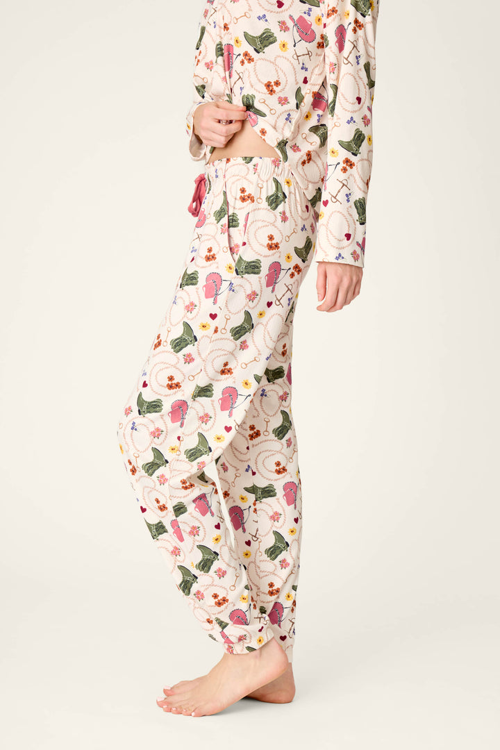 A person wearing P.J. Salvage Saddle Up Western Print Pajama Jogger Pants, shown from the shoulders down and standing barefoot on a light background.