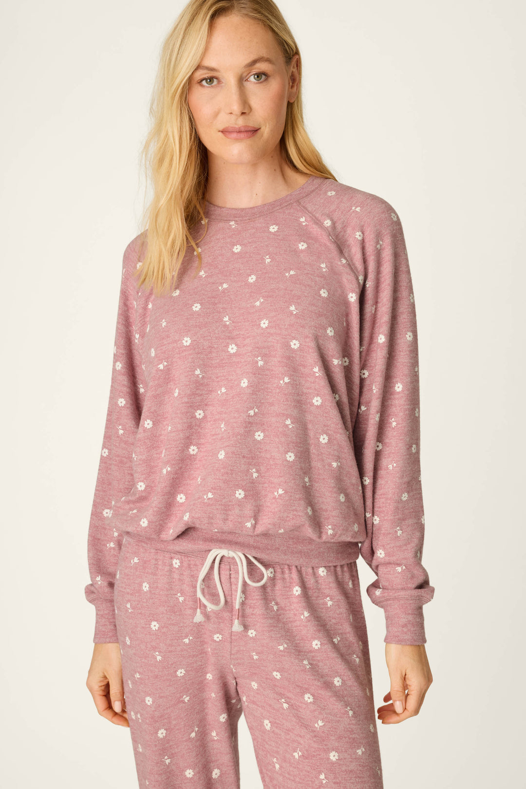 A woman wearing the P.J. Salvage Tiny Blooms Polka Dot Long Sleeve Top and matching pants with delicate white floral prints stands in front of a plain background, looking at the camera with a slight smile.