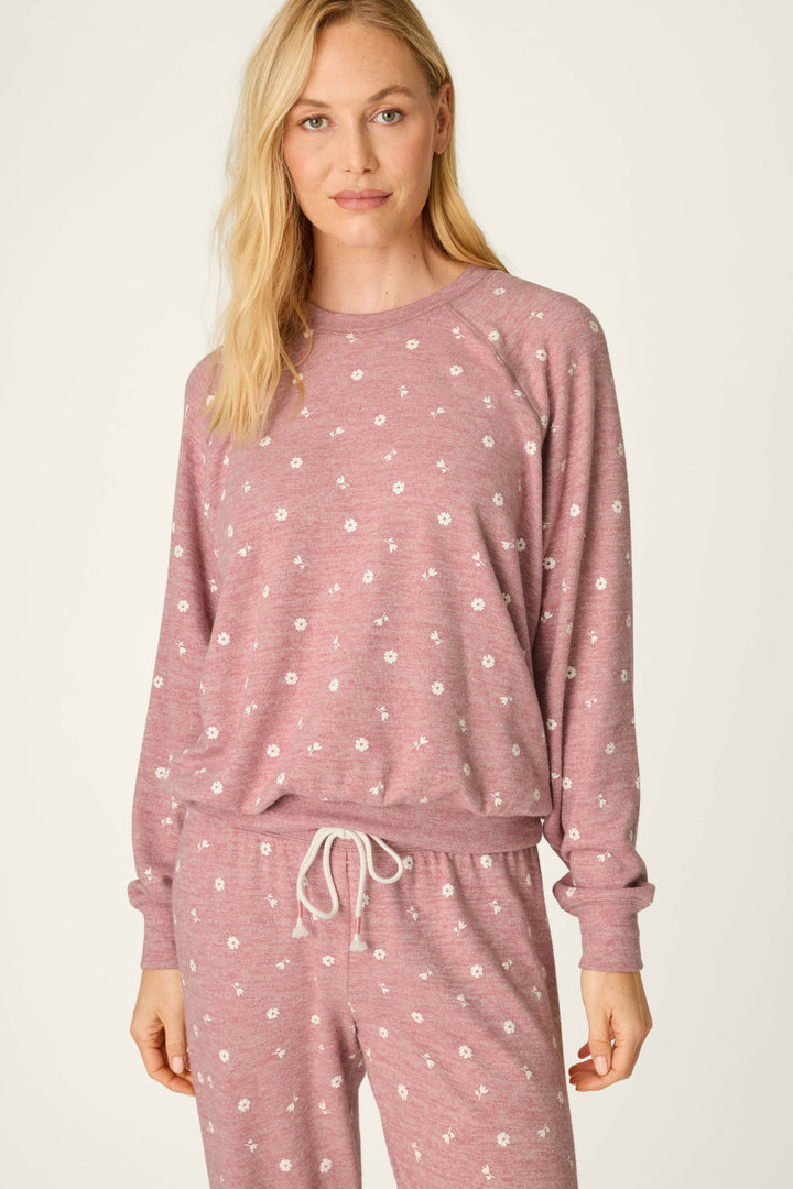 A woman wearing the P.J. Salvage Tiny Blooms Polka Dot Long Sleeve Top and matching pants with delicate white floral prints stands in front of a plain background, looking at the camera with a slight smile.