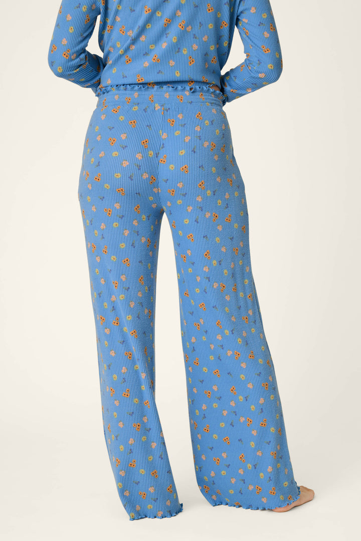 A person wearing P.J. Salvage Tiny Blooms Paris Blue Floral Print Pajama Pants is shown from the back against a plain light background.