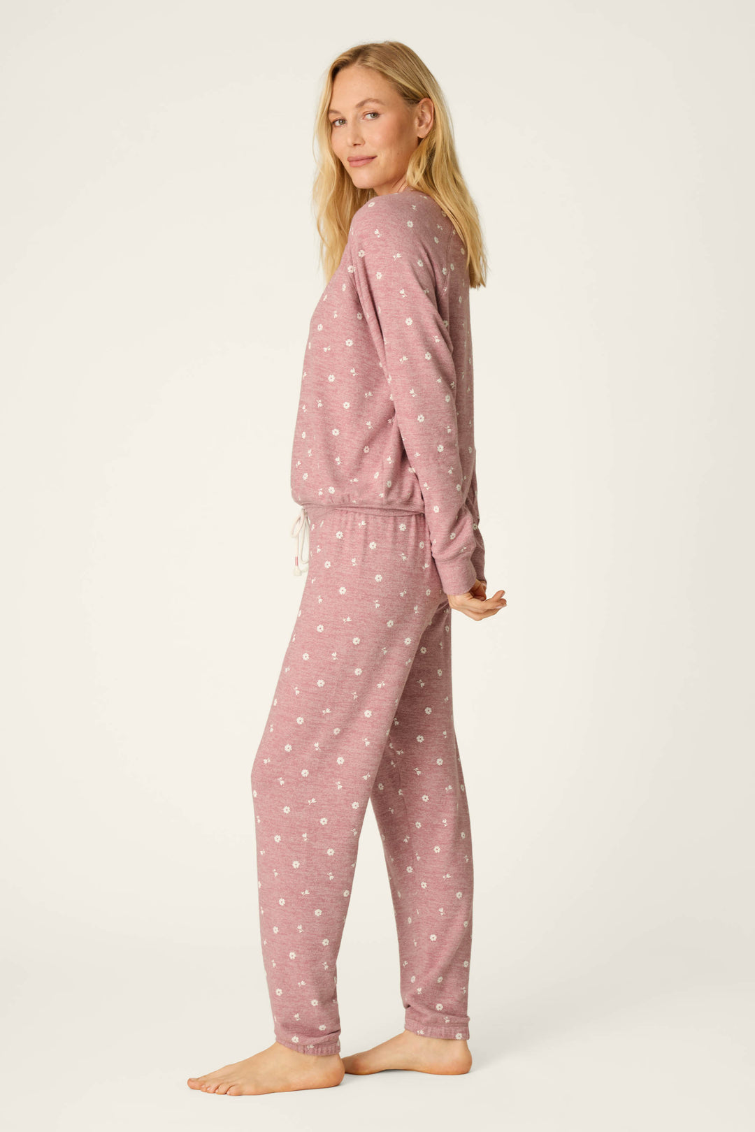 A woman with long blonde hair stands barefoot in profile, wearing the P.J. Salvage Tiny Blooms Polka Dot Long Sleeve PJ Set against a plain light background.