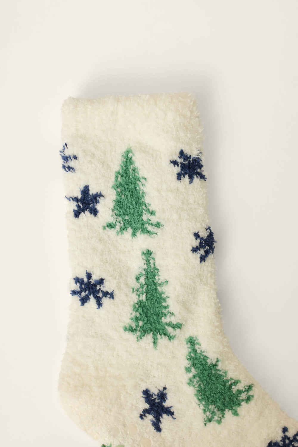 A pair of P.J. Salvage "Under the Stars Tree & Star Print Socks" featuring green Christmas trees and blue snowflakes on a fluffy white background.