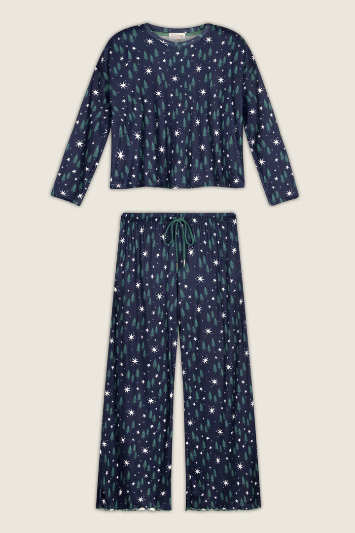 The P.J. Salvage “Under the Stars Magical Forest Print” Long Sleeve Lounge Set is a two-piece pajama set in navy blue, featuring a charming white and green star pattern. The set includes a long-sleeve top and wide-leg pants with a drawstring waist, displayed on a plain background.