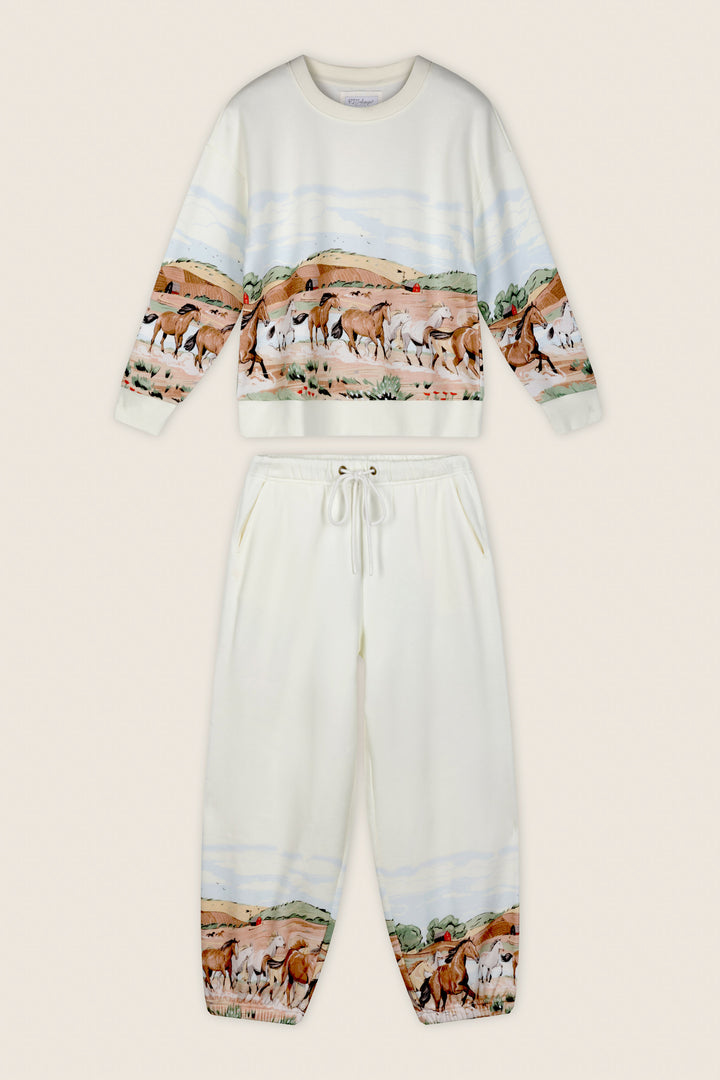 The P.J. Salvage Western Ways Untamed Spirit Frankie Sweatshirt is a cream-colored top featuring a printed landscape of wild horses, hills, and trees wrapping around the midsection.