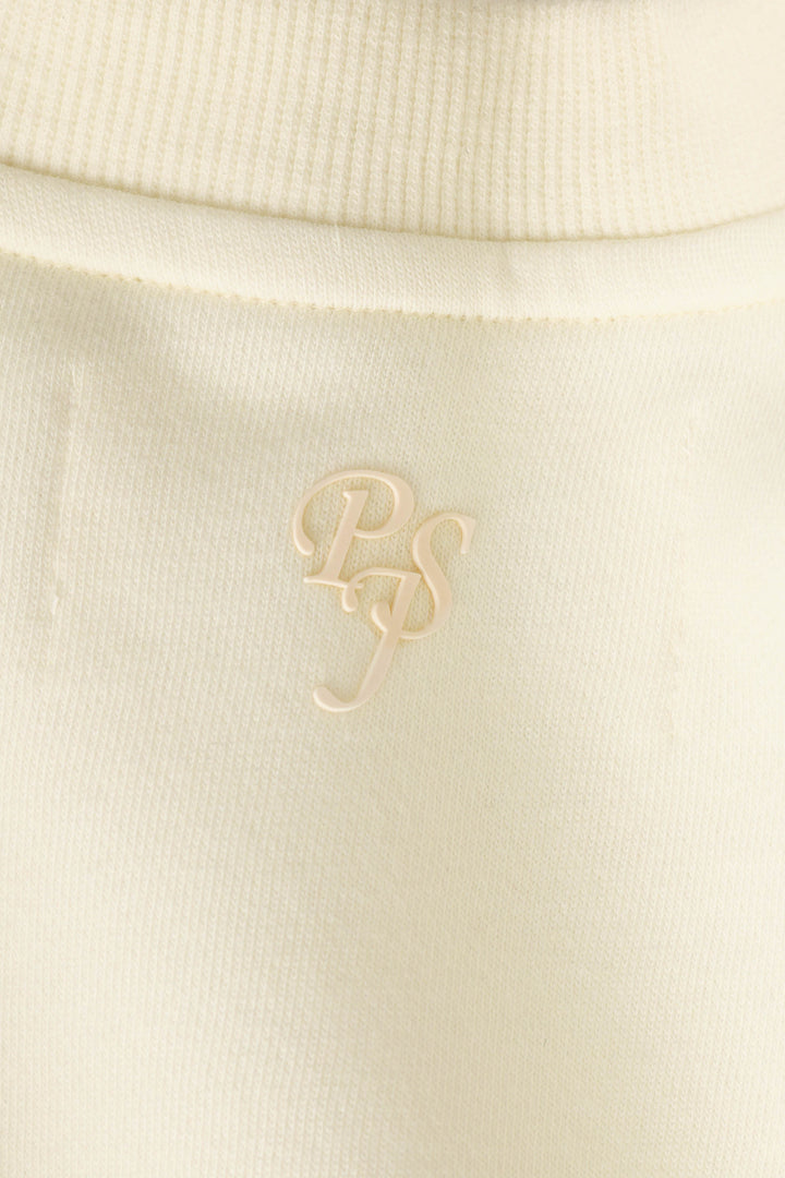 Close-up of a cream-colored ribbed fabric on the P.J. Salvage Western Ways Untamed Spirit Frankie Sweatshirt, featuring the overlapping letters “PS” embroidered or printed in a slightly glossy, matching cream color.