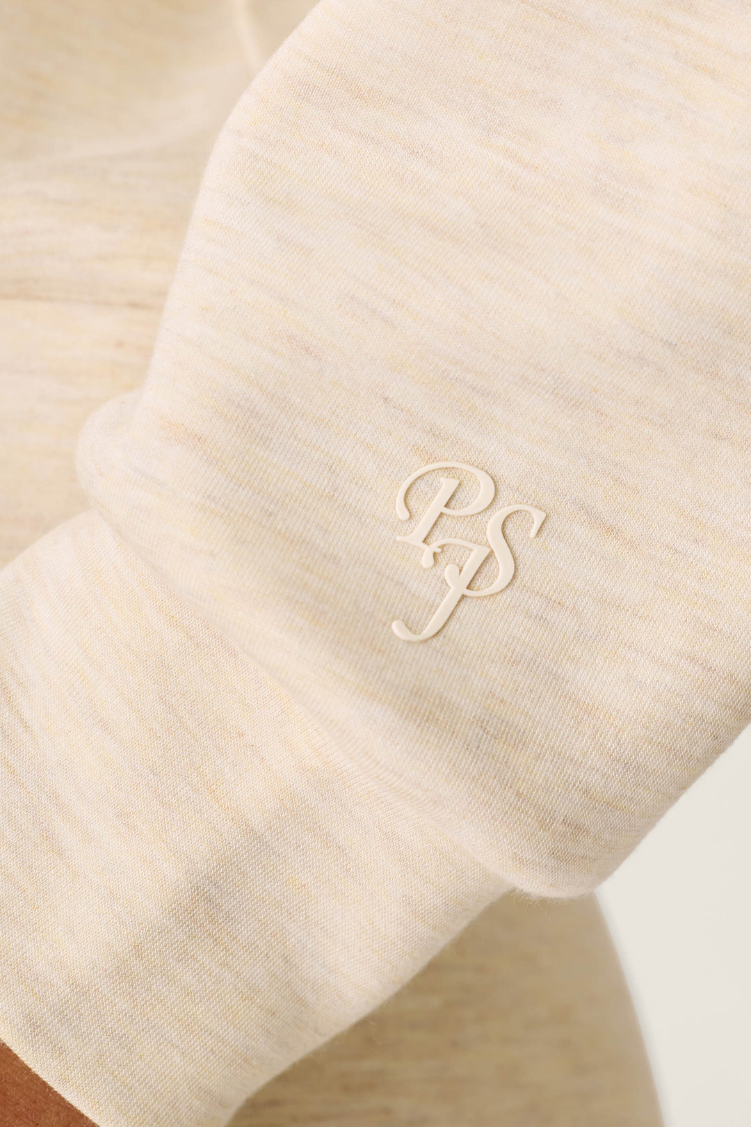 A close-up of the cream-colored sleeve of the P.J. Salvage Western Ways Good Luck Club Over Night Pullover, featuring white embroidered “PSJ” initials near the cuff.