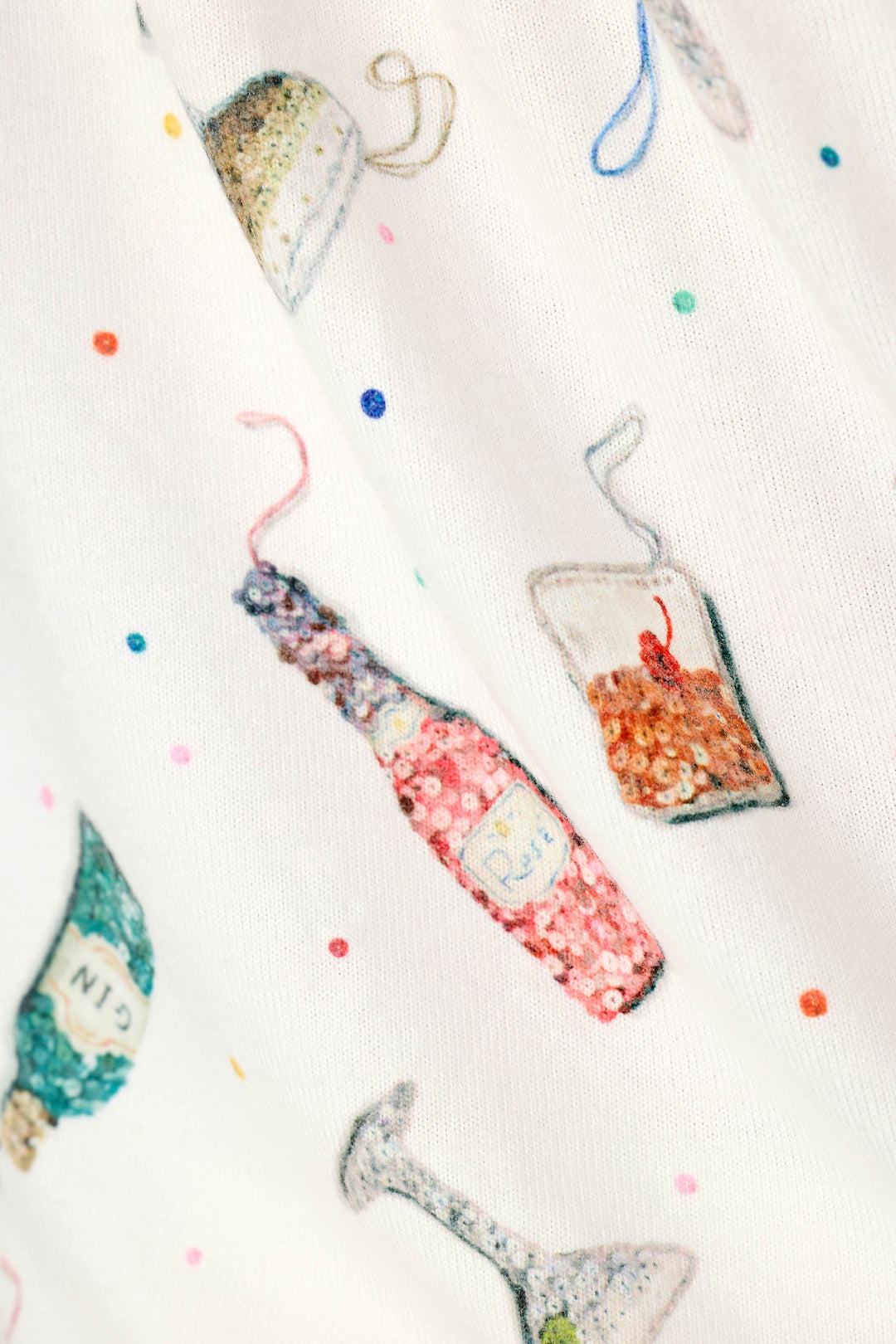 A close-up of a white fabric featuring a whimsical, hand-drawn style print of sequin cocktail ornaments and accented with small multicolored polka dots.