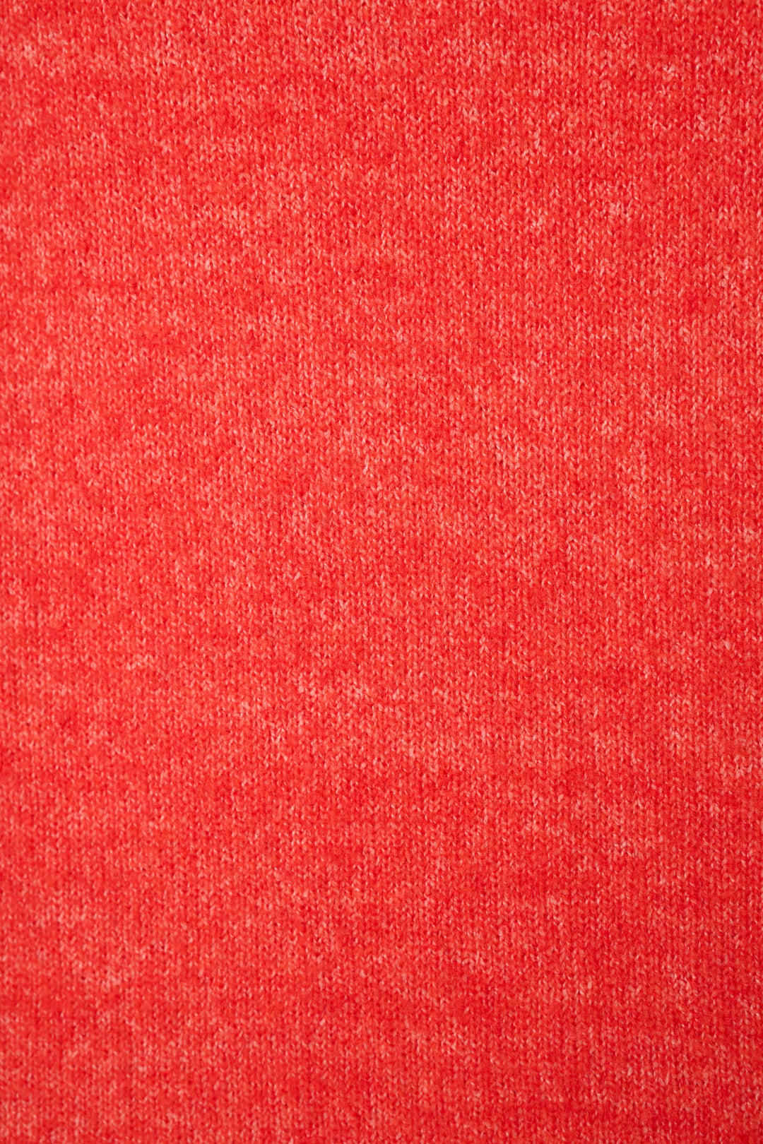A close-up of a heathered red sweater fabric texture filling the entire frame.