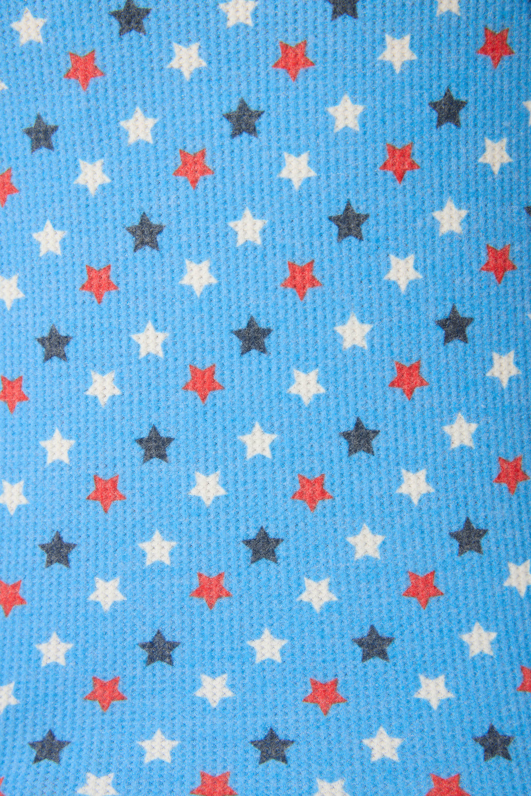 Blue textured fabric with red, white, and black five-pointed stars arranged in a regular grid pattern.