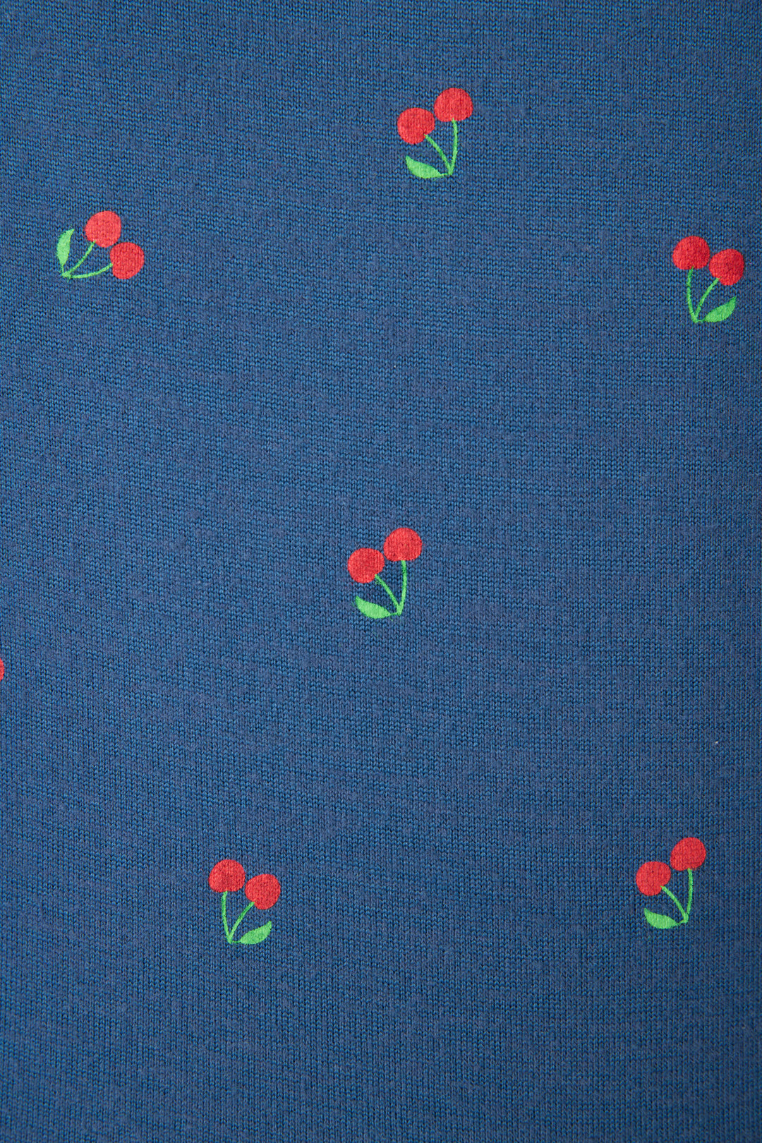 Blue fabric with a repeating pattern of small red cherries and green leaves, evenly spaced across the surface.