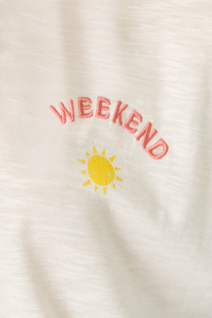 The P.J. Salvage Sunday Funday Embroidered "Weekend" T-Shirt features cream-colored fabric with "WEEKEND" in pink embroidery and a small yellow sun design above.