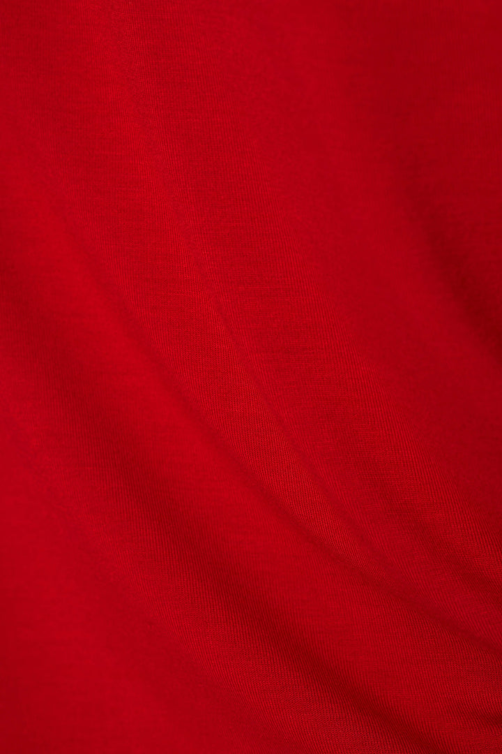 A close-up of bright red fabric with soft folds and a fine knit texture.