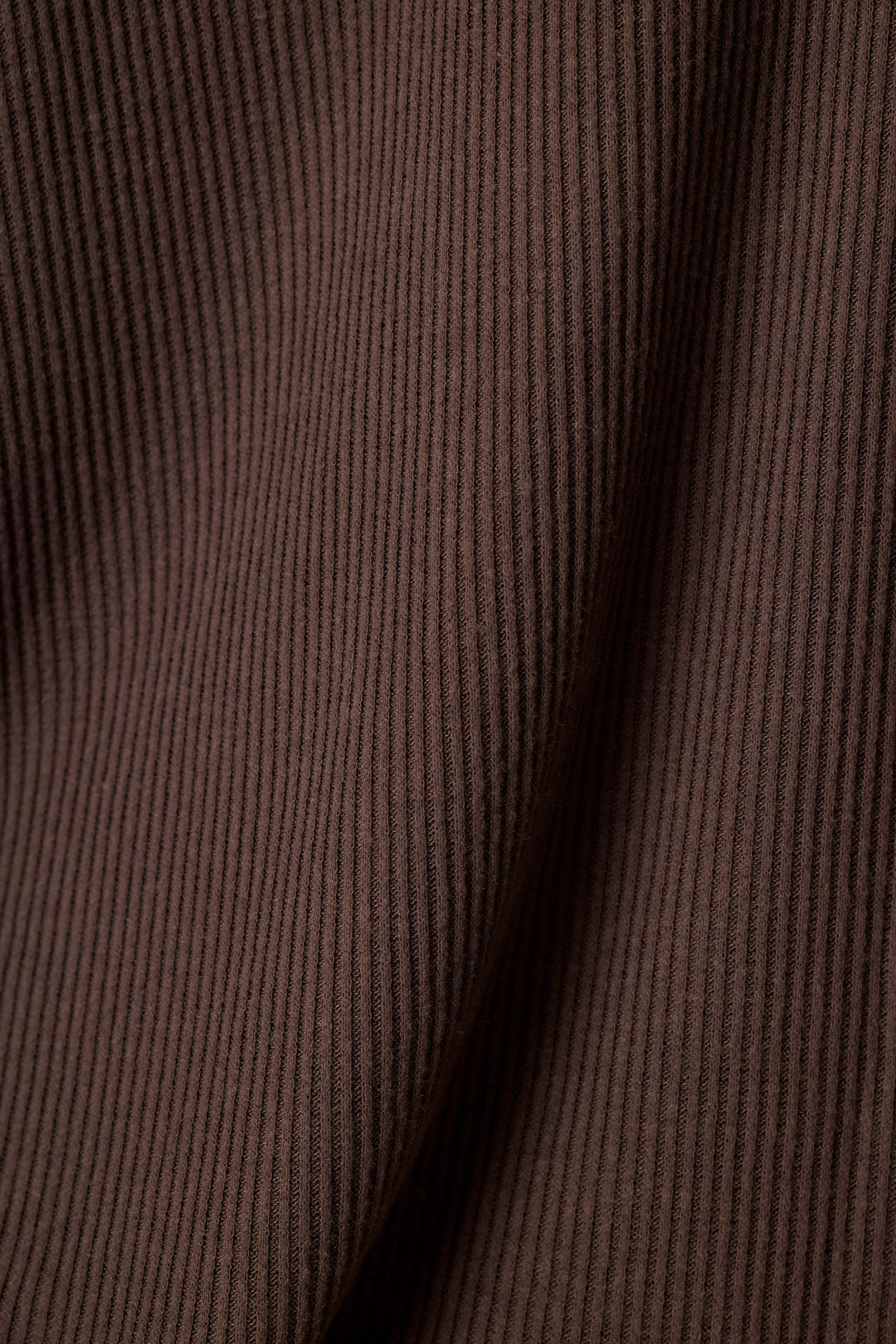 Close-up of a dark brown ribbed fabric texture with soft folds and vertical ridges.