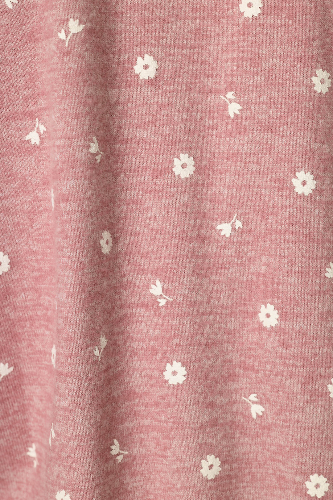 A close-up of a dusty pink heathered fabric with a delicate white floral and leaf pattern scattered across it.