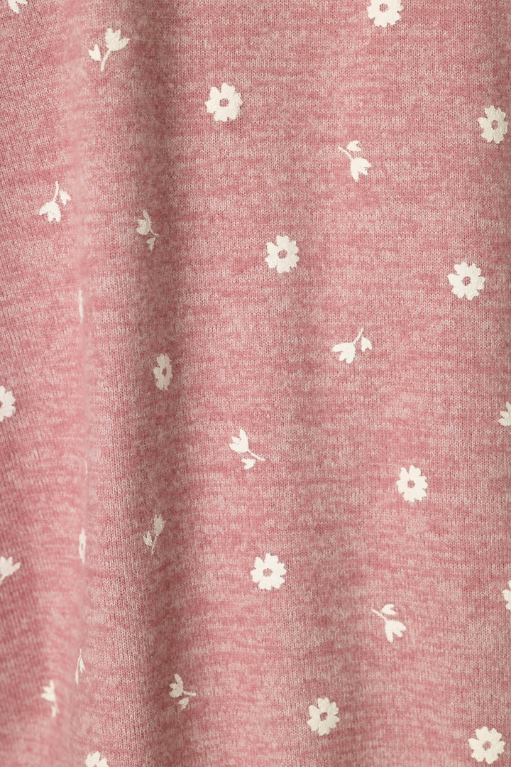 A close-up of a dusty pink heathered fabric with a delicate white floral and leaf pattern scattered across it.